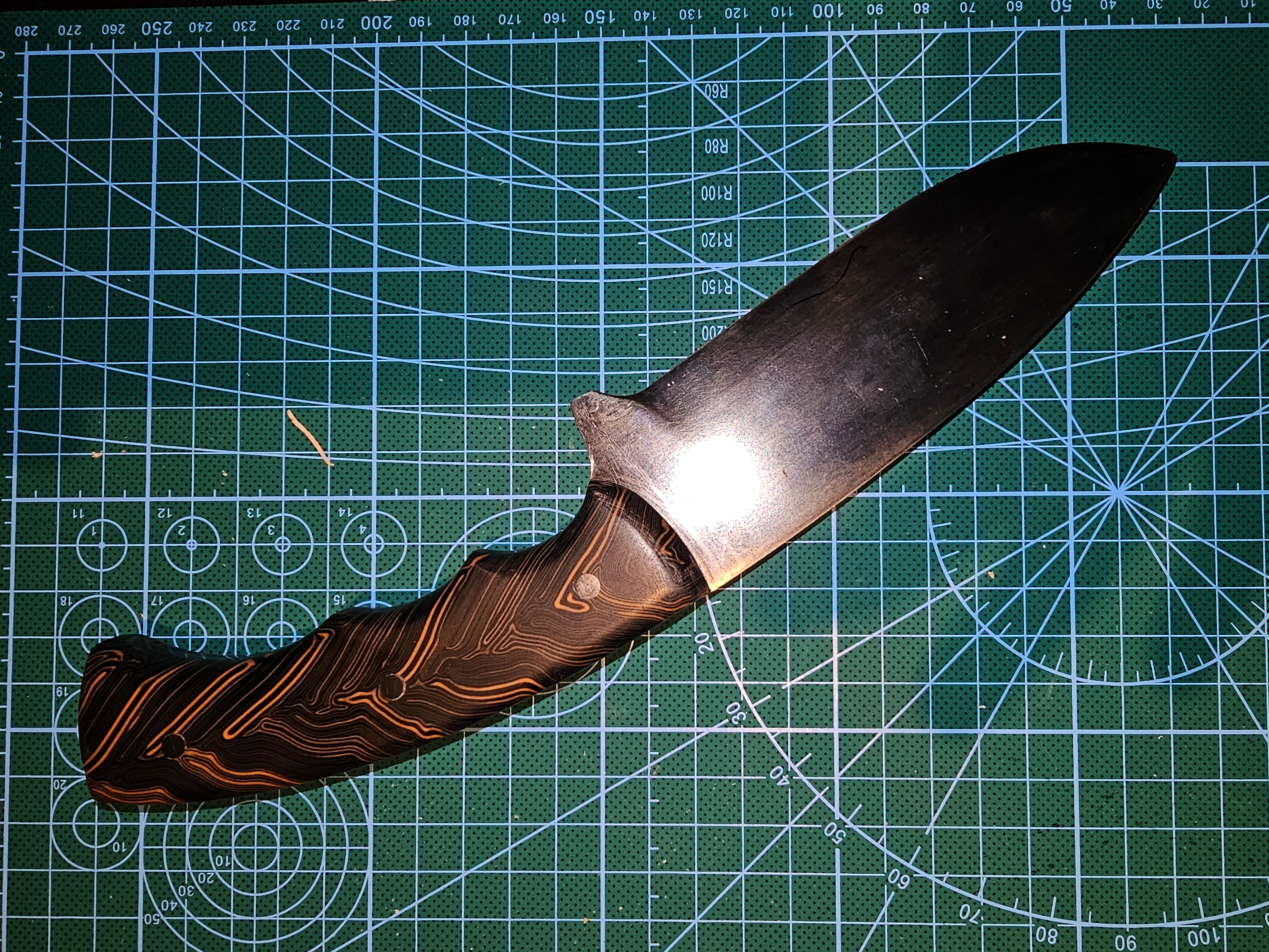 Custom fixed blade knife with black and orange micarta handle on grid mat