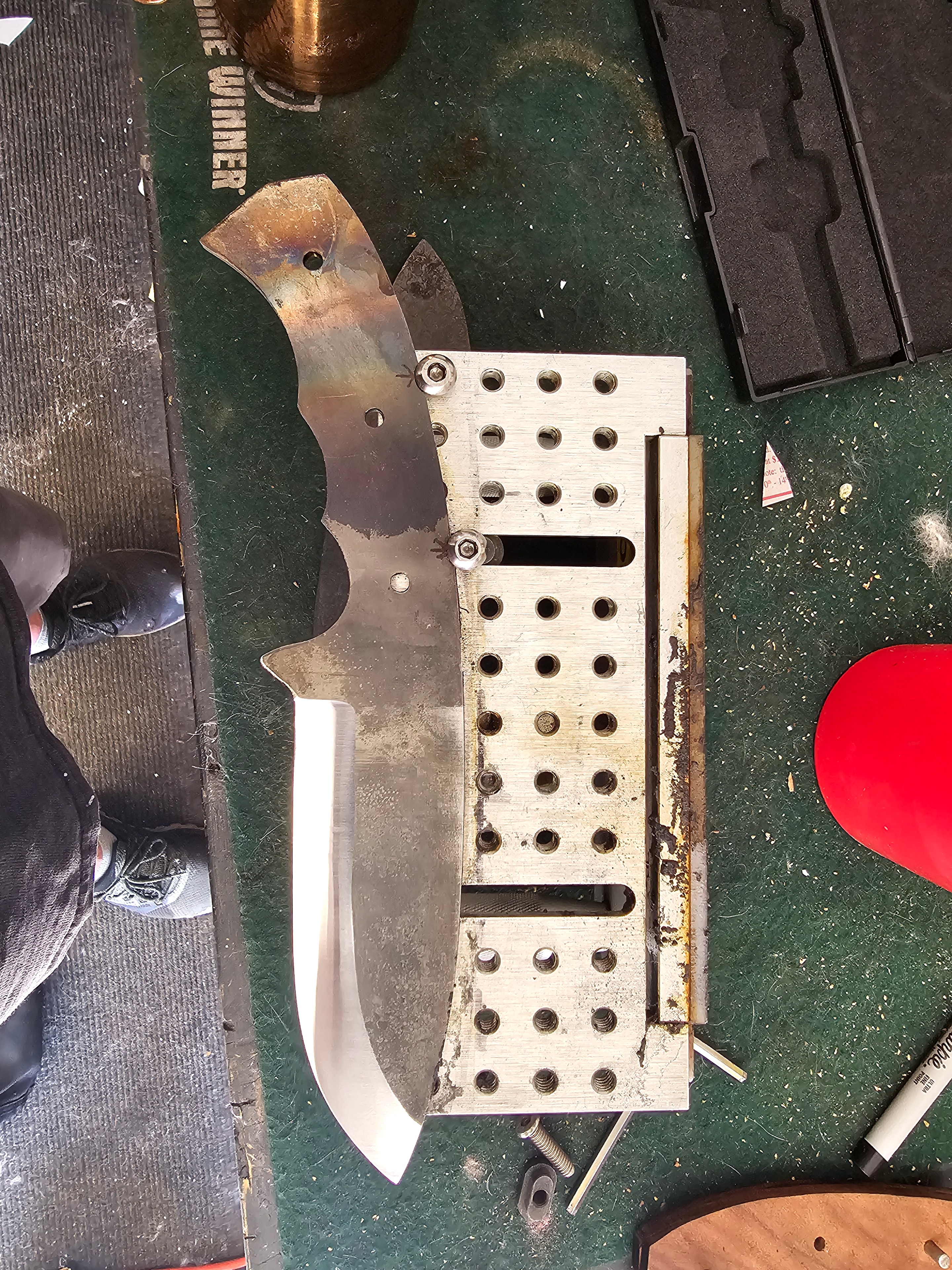 Custom knife blade clamped in machinist jig during build process