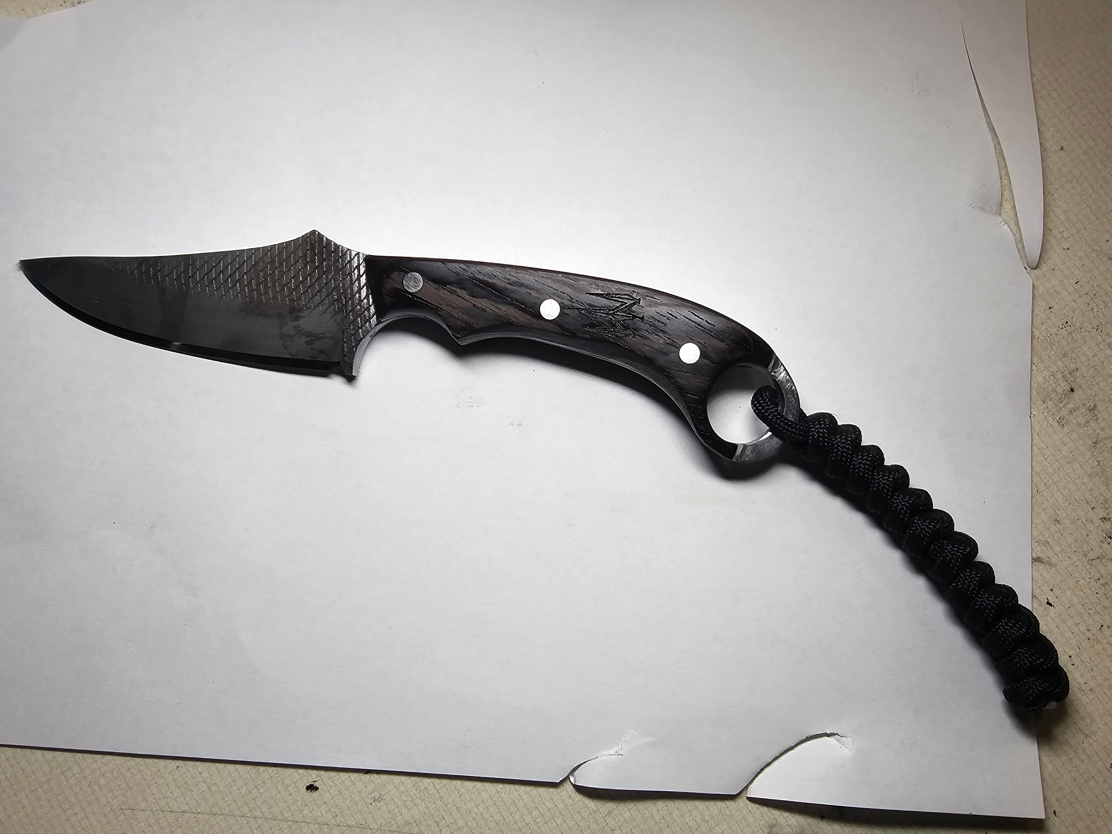 Finished karambit knife with dark wood handle and black paracord lanyard