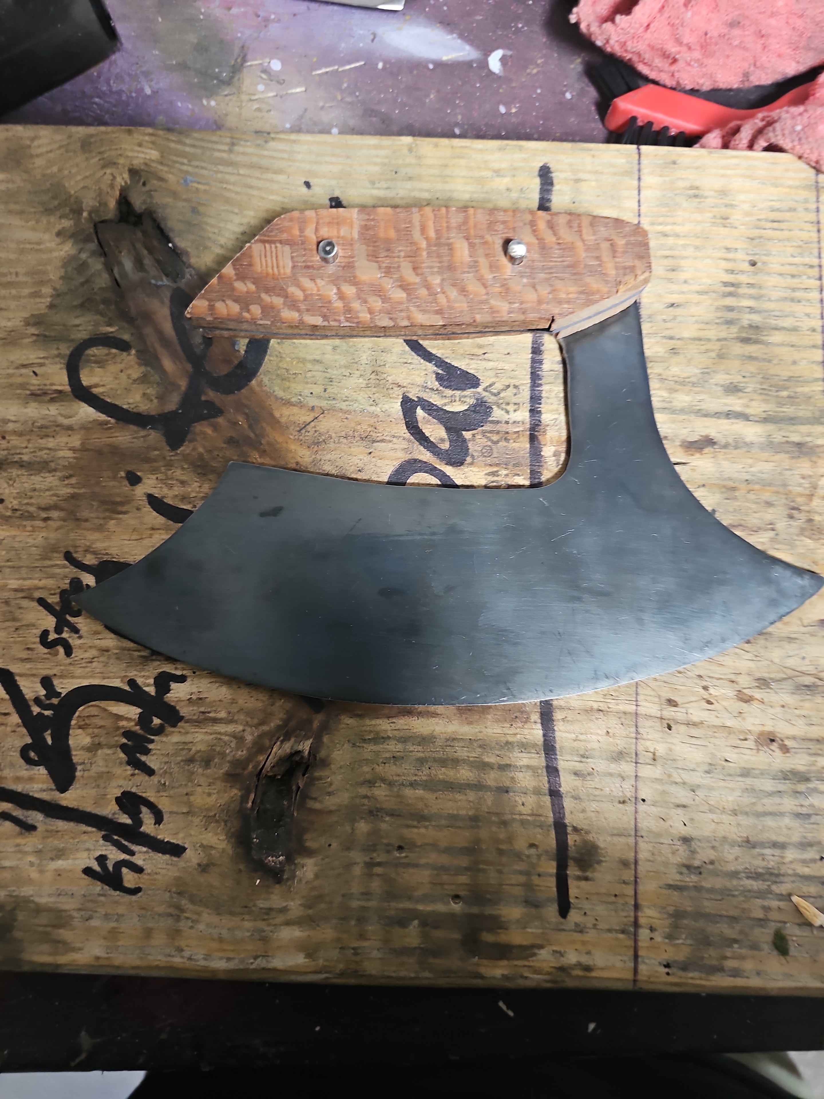 Handcrafted ulu-style axe blade with wood handle on workbench